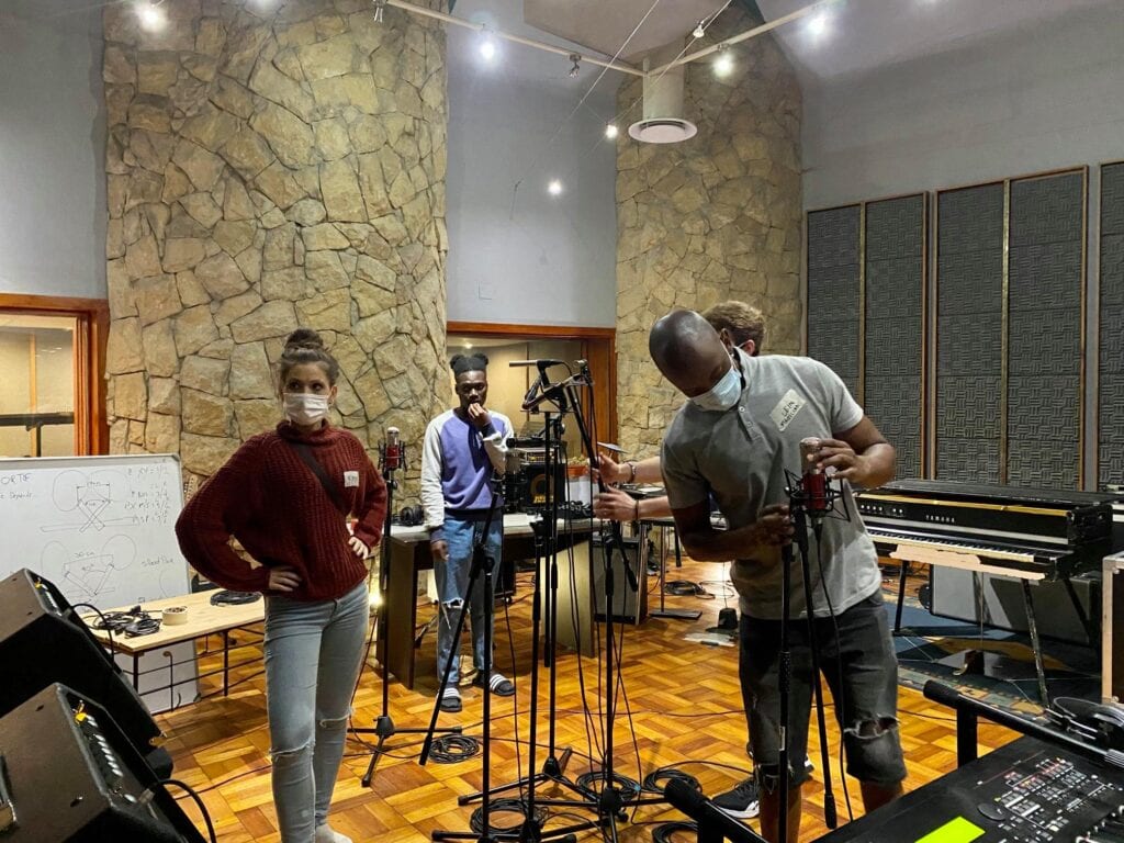 Interview Music Producer and students setting up equipment and mic stands in studio one woman and three men